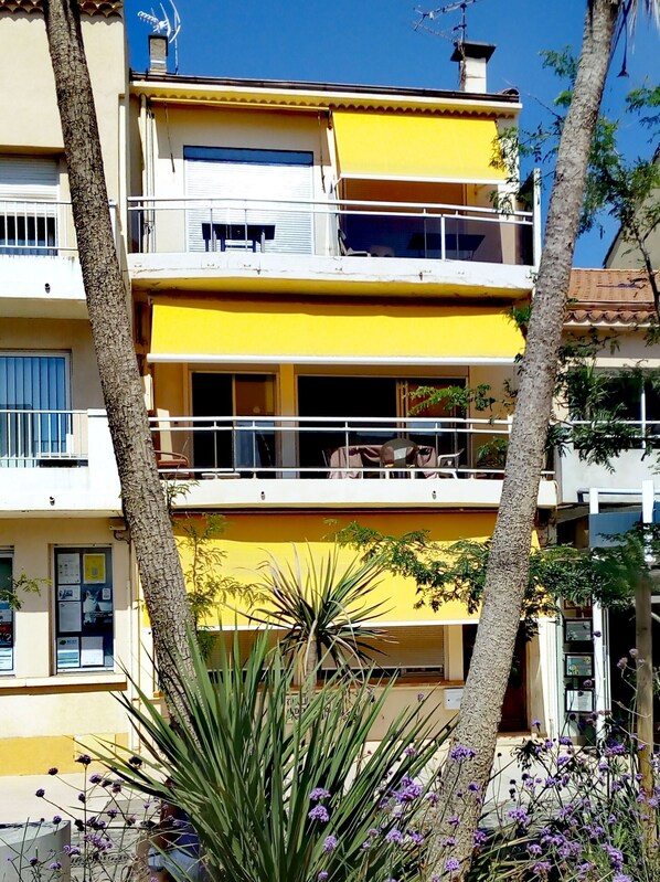 Un edificio de varios pisos con balcones y fachada amarilla.
