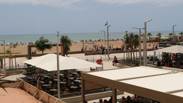 Um restaurante à beira-mar com mesas ao ar livre e vista para o mar.