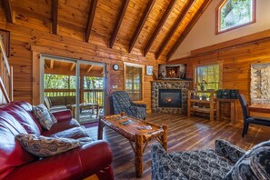 Ein rustikales Holzhaus-Interieur mit Kamin aus Stein, Ledermöbeln und einer Holzbalkendecke.