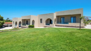 A modern building with multiple rooms, a well-maintained lawn, and a clear blue sky. - Seafront luxury apartment with amazing sunset view 3 (Stavros,Chania)