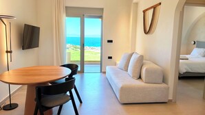 A modern living room with a dining area, a sofa, a TV, and a view of the sea. - Seafront luxury apartment with amazing sunset view 3 (Stavros,Chania)