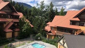 A resort with multiple buildings, a swimming pool, and a mountainous backdrop.