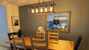 A dining area with a wooden table and chairs, a chandelier, and a mirror on the wall.