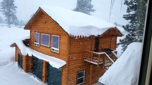 A wooden cabin with a snow-covered roof and windows, surrounded by a snowy landscape.