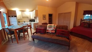 A cozy living area with a sofa, a dining table, and a kitchen in the background.