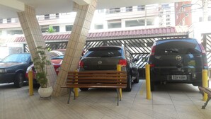 A parking area with multiple cars, a bench, and a potted plant. - Furnished apartment near the beach (Canto do Forte)