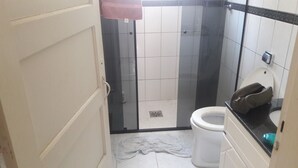 A bathroom with a glass-enclosed shower, a toilet, and a sink. - Furnished apartment near the beach (Canto do Forte)