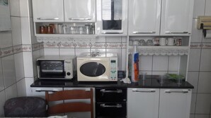 A kitchen with white cabinets, a toaster, a microwave, and a sink. - Furnished apartment near the beach (Canto do Forte)