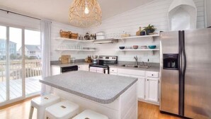 Une cuisine moderne avec des meubles blancs, un réfrigérateur en acier inoxydable et un grand îlot central doté de tabourets de bar.