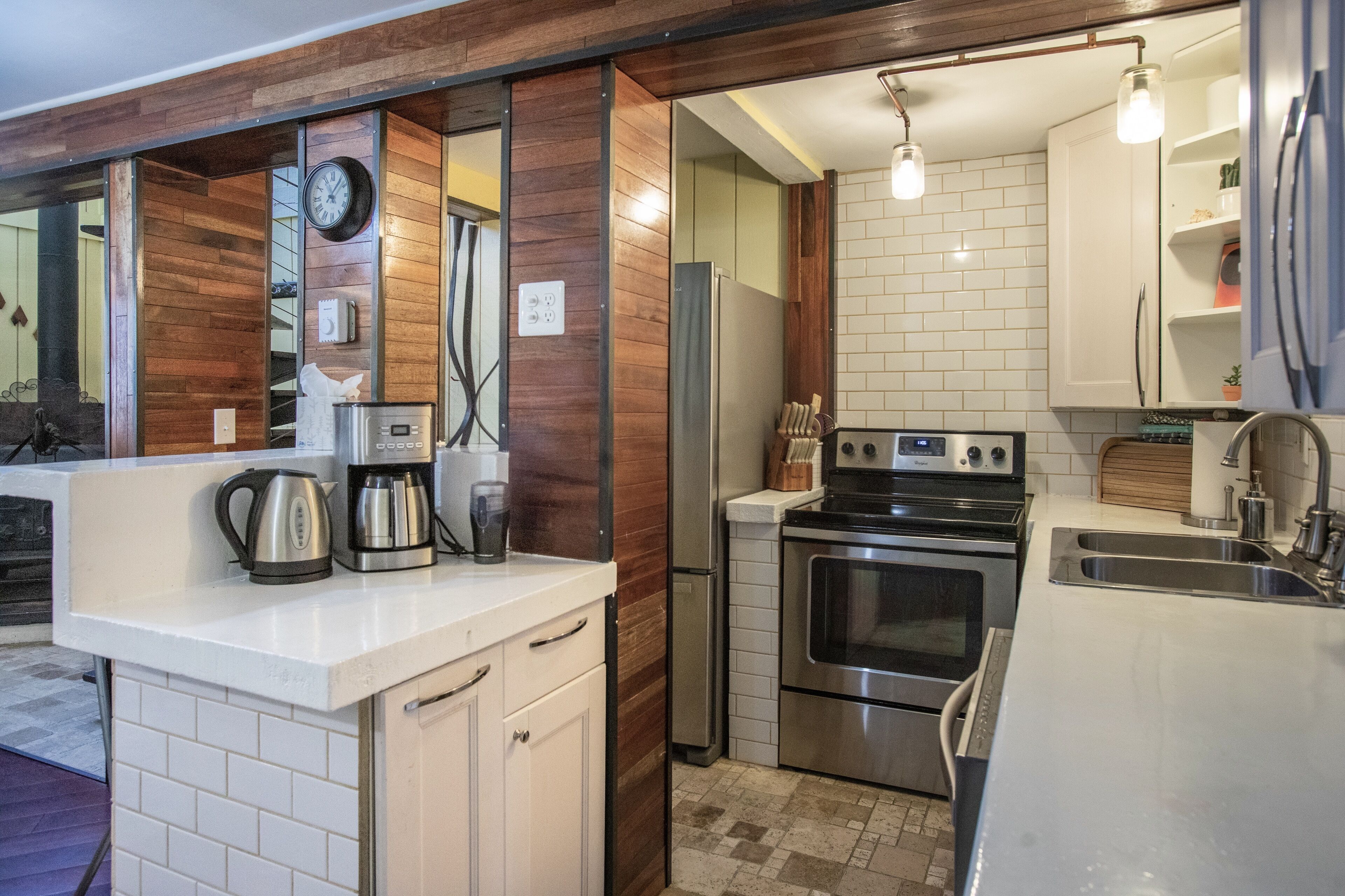 A modern kitchen with white cabinets, stainless steel appliances, and a wooden accent wall.