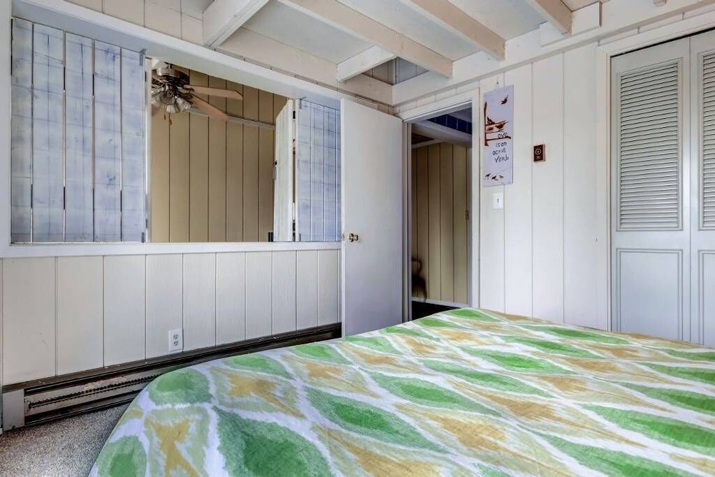 A room with a bed, a wardrobe, and a door leading to another room.