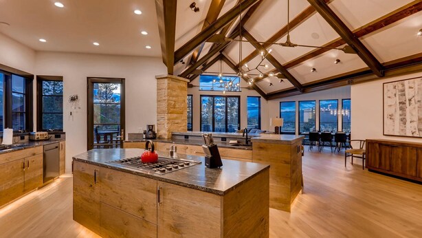 Una cocina amplia con una isla central, ventanas grandes y un techo alto con vigas a la vista.