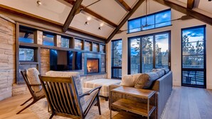 Un salón amplio con chimenea, ventanas grandes y un techo alto con vigas a la vista.
