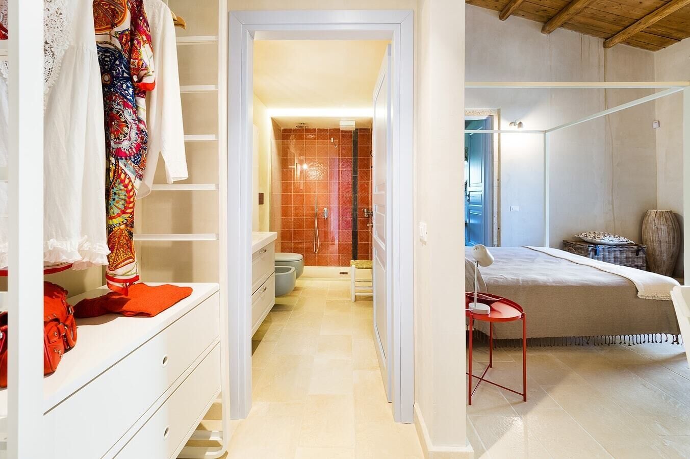 Une chambre à coucher moderne avec un lit, une table de chevet et un fauteuil rouge.