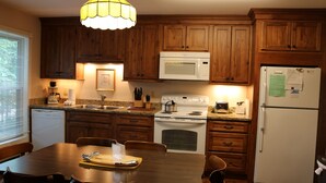 A kitchen with wooden cabinets, a white stove, a microwave, and a refrigerator. - 'Ski Shack' Condo w/ Private Deck (Sugar Mountain)