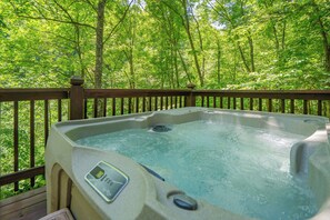 A hot tub on a wooden deck with a forest view.
