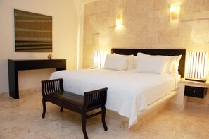 Une chambre d’hôtel bien aménagée, avec un grand lit, une table de chevet, un banc et une œuvre d’art accrochée au mur.
