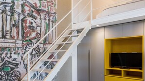 A modern living room with a staircase, a yellow sofa, and a mural on the wall. - Suite behind the cathedral (Palermo)