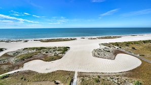 An aerial view of a beach with a large sandy area and a clear blue sky.
