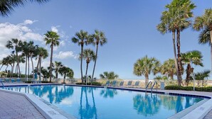 A swimming pool with palm trees and lounge chairs.