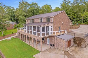 Une maison à deux étages dotée d’un balcon, de piliers en pierre et d’un patio couvert.