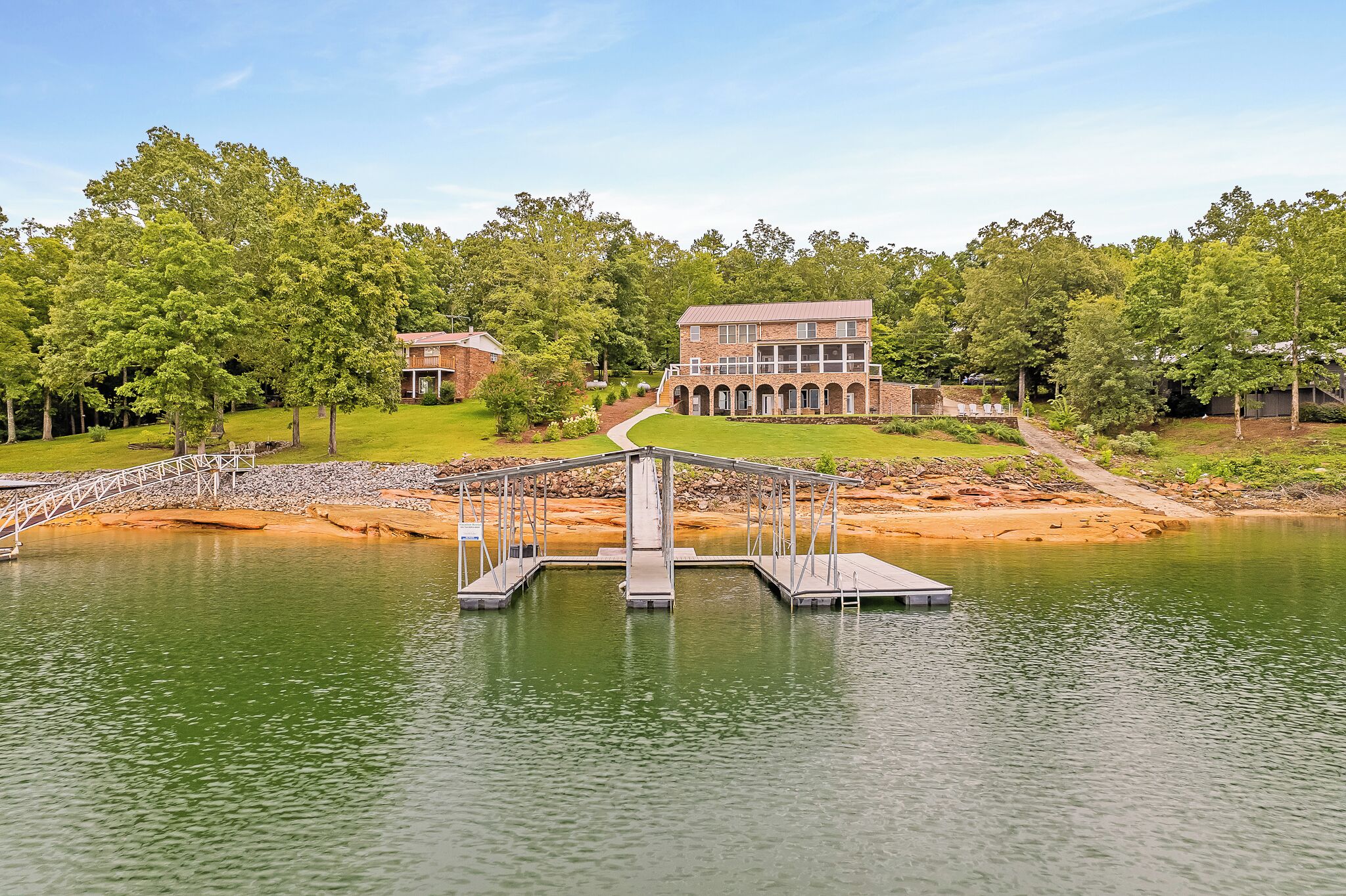 A riverside property with a bridge, a multi-story building, and a well-maintained lawn.