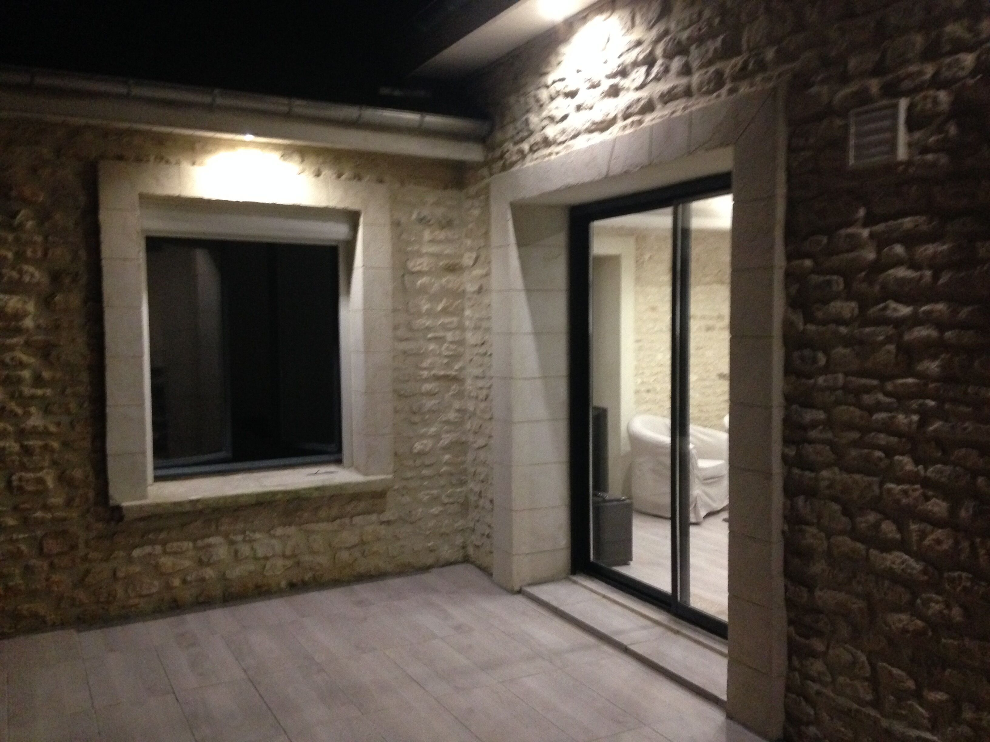 A stone-walled room with a window and a sliding glass door leading to a bathroom.