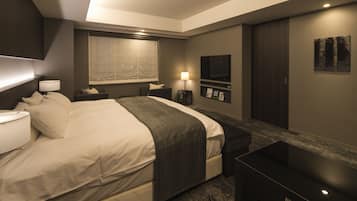Quarto de hotel moderno com uma cama grande, mesas de cabeceira, escrivaninha, televisão e guarda-roupa.