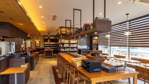 A modern cafe interior with wooden furniture, a long counter, and a variety of bookshelves.