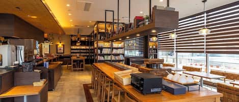 A modern cafe interior with wooden furniture, a long counter, and a variety of bookshelves.