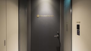 A modern elevator with a dark door and a sign reading "GRAN EXCELLENCE AREA".
