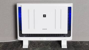 A white DUSKIN air purifier with a control panel and ventilation slots, standing on a textured carpet against a grey wall.