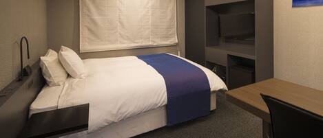 A hotel room with a bed, a desk, a chair, a TV, and a window with blinds.