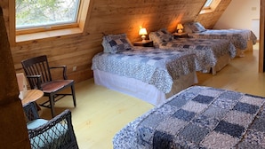 A cozy attic bedroom with two beds, a wooden chair, and a small table. - Spacious Cottage Overlooking Bass Harbor with Sweeping Front Lawn (Bass Harbor)