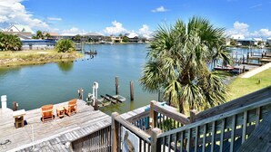 A waterfront property with a dock, chairs, and a palm tree. - Sunset Key - Soundfront with Boat Dock, 3 Bedrooms, 2 Baths, Sleeps 9. (Dauphin Island)