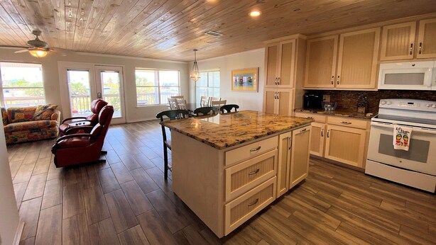 A spacious kitchen with wooden cabinets, a granite countertop, and a built-in oven. - Sunset Key - Soundfront with Boat Dock, 3 Bedrooms, 2 Baths, Sleeps 9. (Dauphin Island)