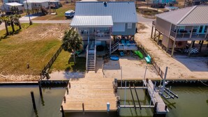 A coastal house with a dock extending into the water. - Sunset Key - Soundfront with Boat Dock, 3 Bedrooms, 2 Baths, Sleeps 9. (Dauphin Island)