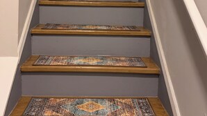 Una escalera con peldaños de madera y un tapete estampado al final.