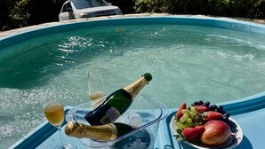Montaje junto a la piscina con una botella de champán, una copa de champán y un plato de fruta.