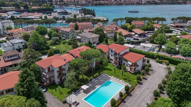 Et boligområde med swimmingpool, huse med røde tage og en lysthavn i baggrunden.