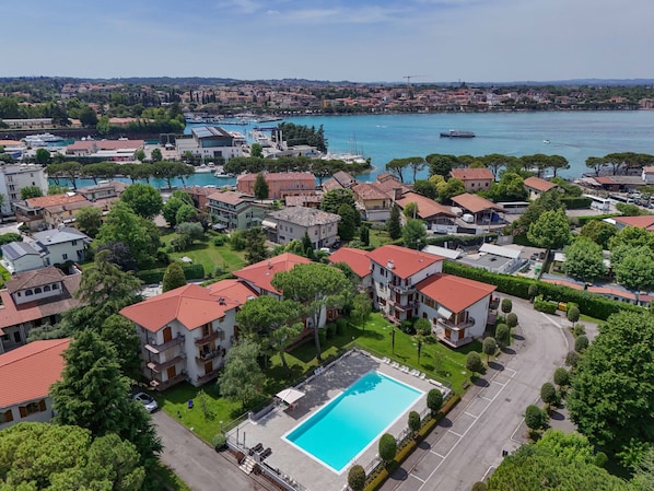 Un quartiere residenziale con una piscina, case dai tetti rossi e un porto turistico sullo sfondo.