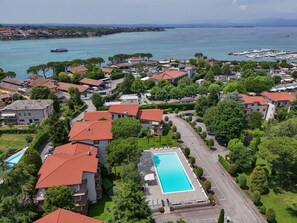 Una zona residenziale con piscina, case a tetto rosso e un porto turistico sullo sfondo.