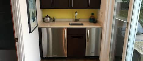 Una cocina compacta con electrodomésticos de acero inoxidable, un fregadero y armarios oscuros.