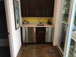 Una cocina compacta con electrodomésticos de acero inoxidable, un fregadero y armarios oscuros.