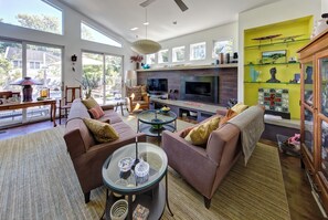 A modern living room with a sofa set, a glass coffee table, and a flat-screen TV.