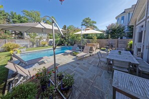 Un patio trasero con piscina, muebles de patio y plantas en macetas.