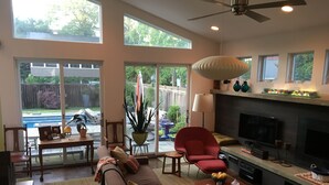 A spacious living room with a fireplace, a red armchair, a sofa, and a dining area with a table and chairs. - 6 Bed/5 Bath with Pool - upgraded beds for 2026 (Rehoboth Beach)