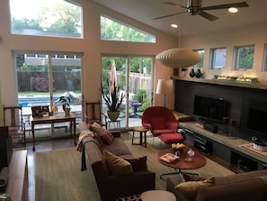 A spacious living room with a fireplace, a red armchair, a sofa, and a dining area with a table and chairs.