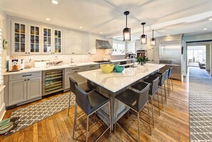 Una cocina moderna con una isla grande, taburetes de bar y electrodomésticos de acero inoxidable.