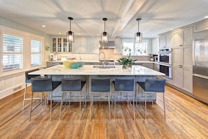 A modern kitchen with a large island, bar stools, stainless steel appliances, and pendant lighting. - Private Pool, Gourmet Kitchen, 2 1/2 Blocks to Beach, Close to Town (Rehoboth Beach)